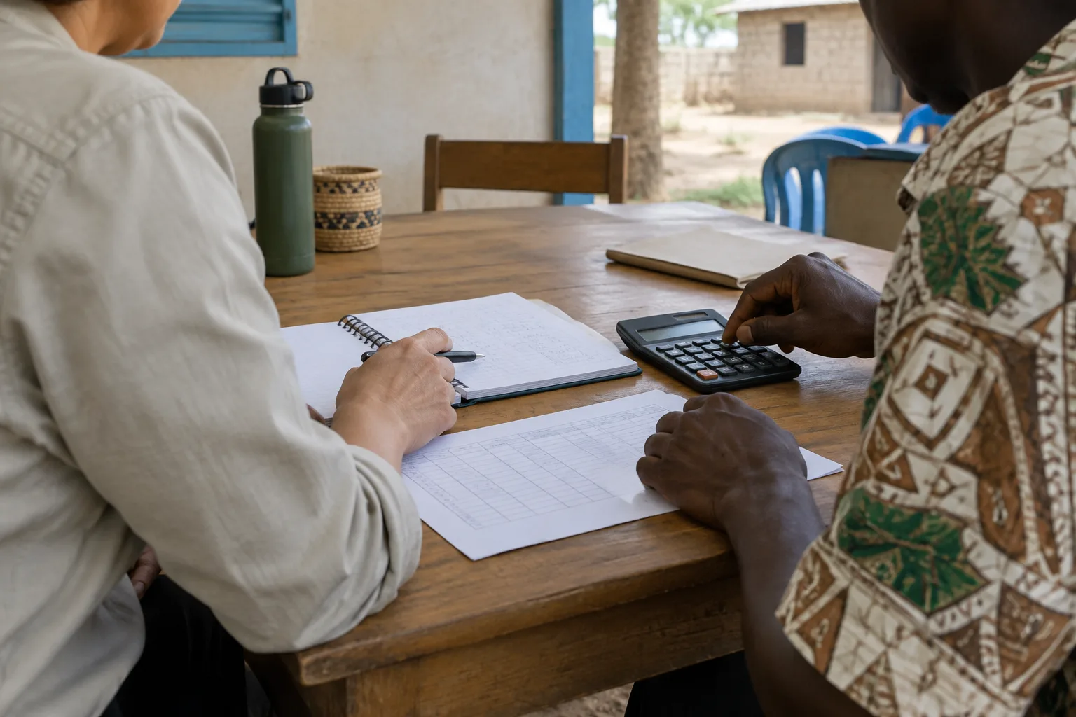 Une coordinatrice et un partenaire local examinent ensemble un budget de mission sur une table.