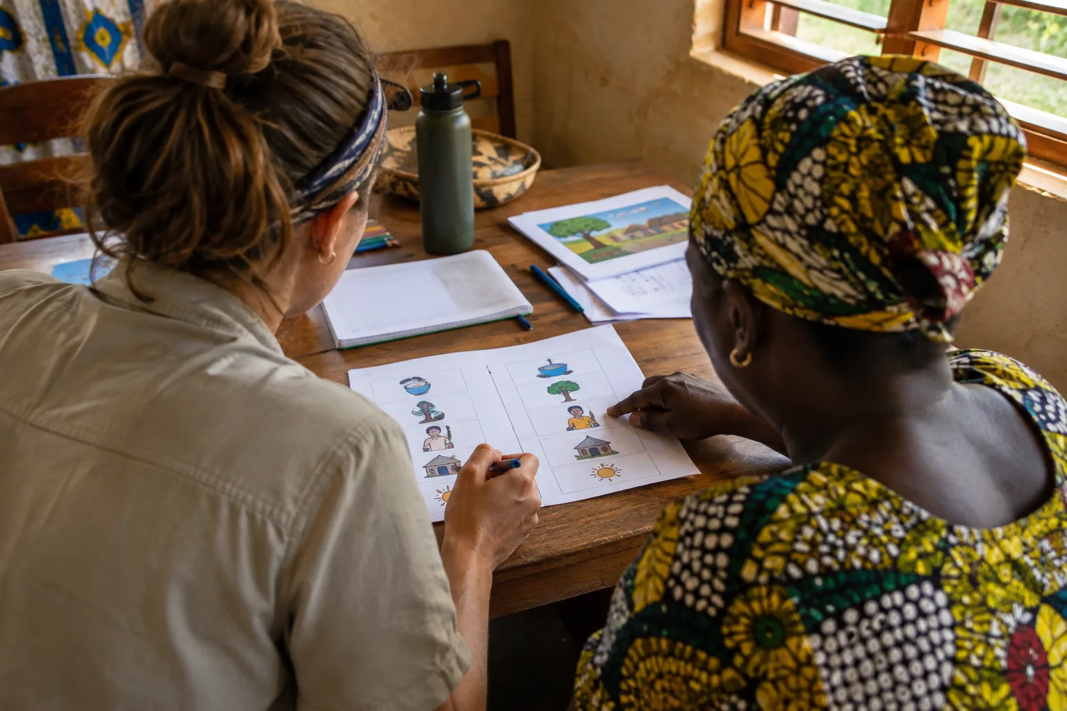 Un bénévole et une coordinatrice locale préparent des supports pour une activité de terrain.