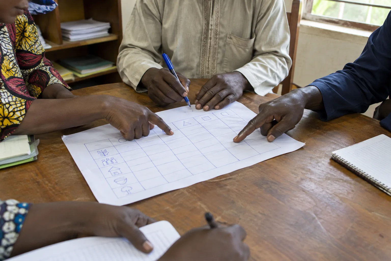 Des membres d’une association examinent ensemble un tableau de suivi papier.
